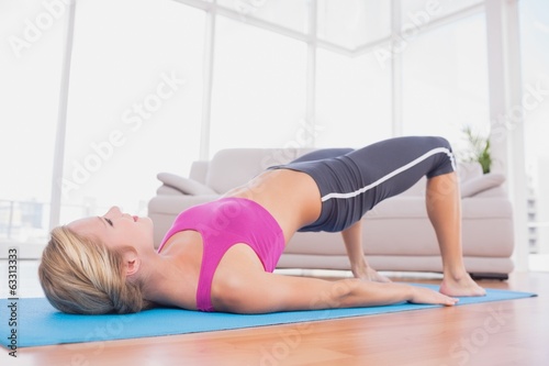 Slim blonde doing pilates on exercise mat