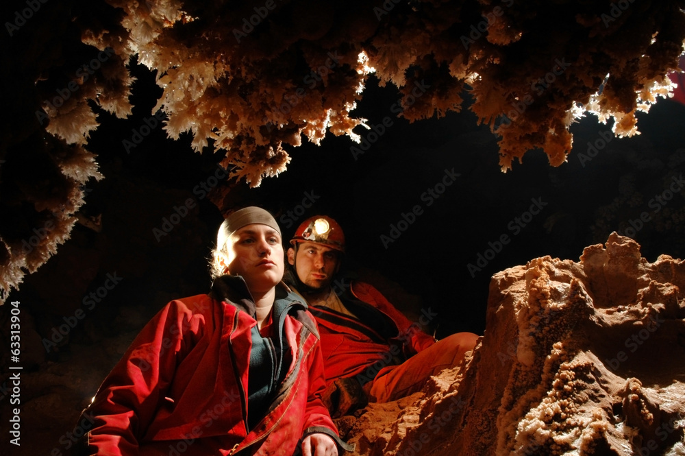 Spelunkers admiring stalactites in a cave Spelunkers admiring stalactites in a cave