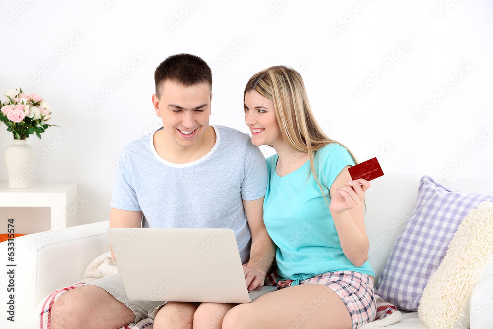 Loving couple sitting with laptop and credit card