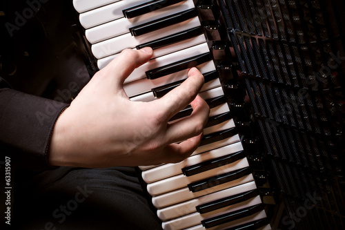 musician plays the accordion against a dark background