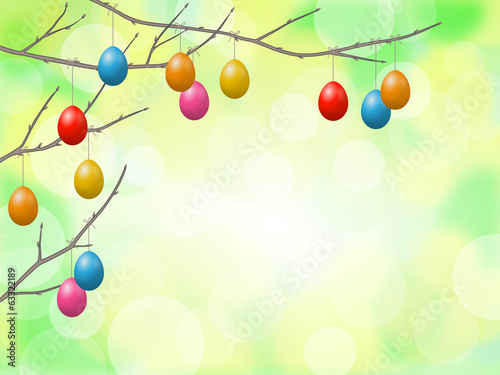 Zweige mit Ostereiern vor gelb-grünem Bokeh-Hintergrund