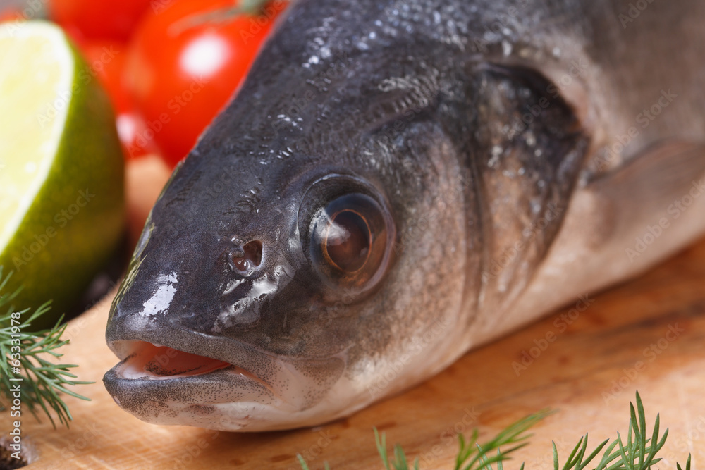 Raw sea bass fish with vegetables close-up front view Raw sea bass fish with vegetables close-up front view