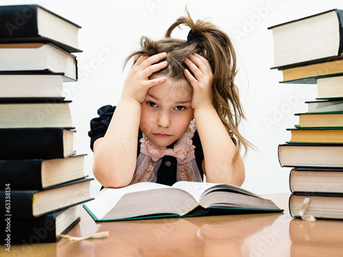 Маленькая усталая девочка среди книг