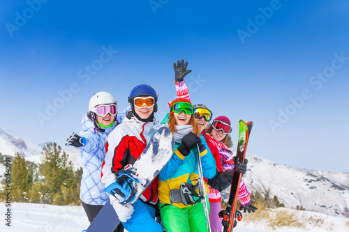 Five happy friends with snowboards and skis