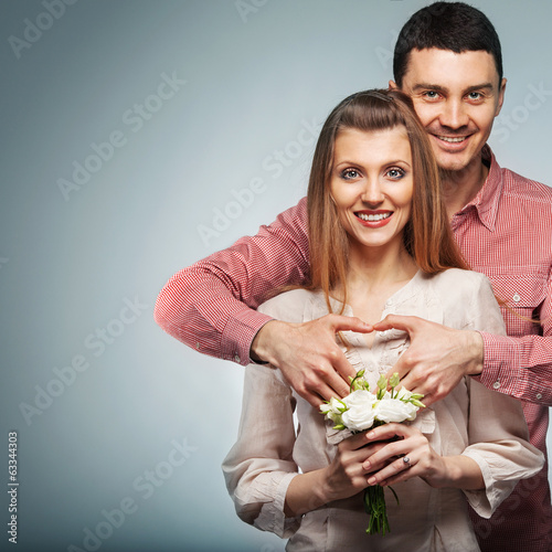 Young couple in love make a heart and hands are holding bouquet