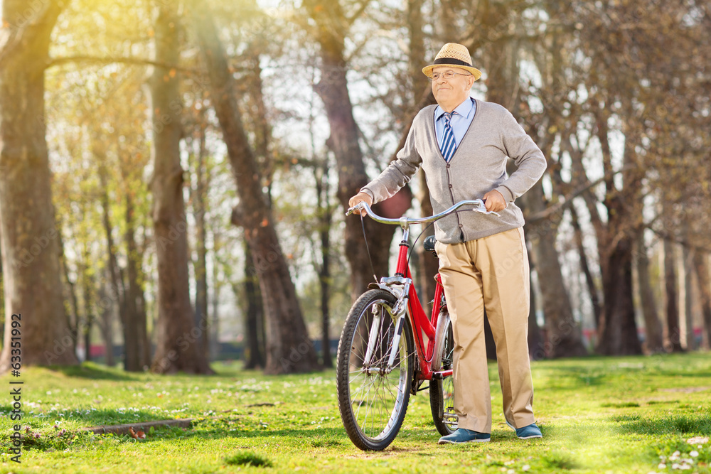 Obraz premium An elderly pushing his bike in the park