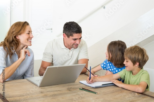 Parents with laptop assisting children coloring