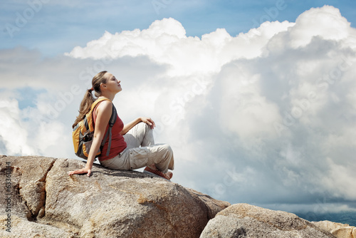 Young woman sitting on a rock with backpack. photo