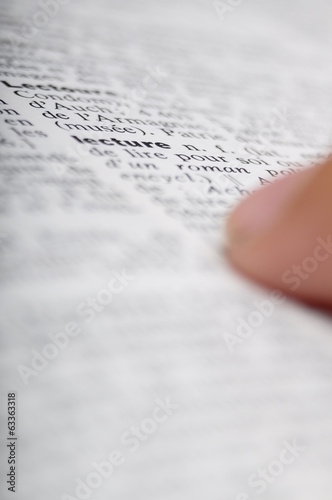 Child reading with his finger on dictionary photo