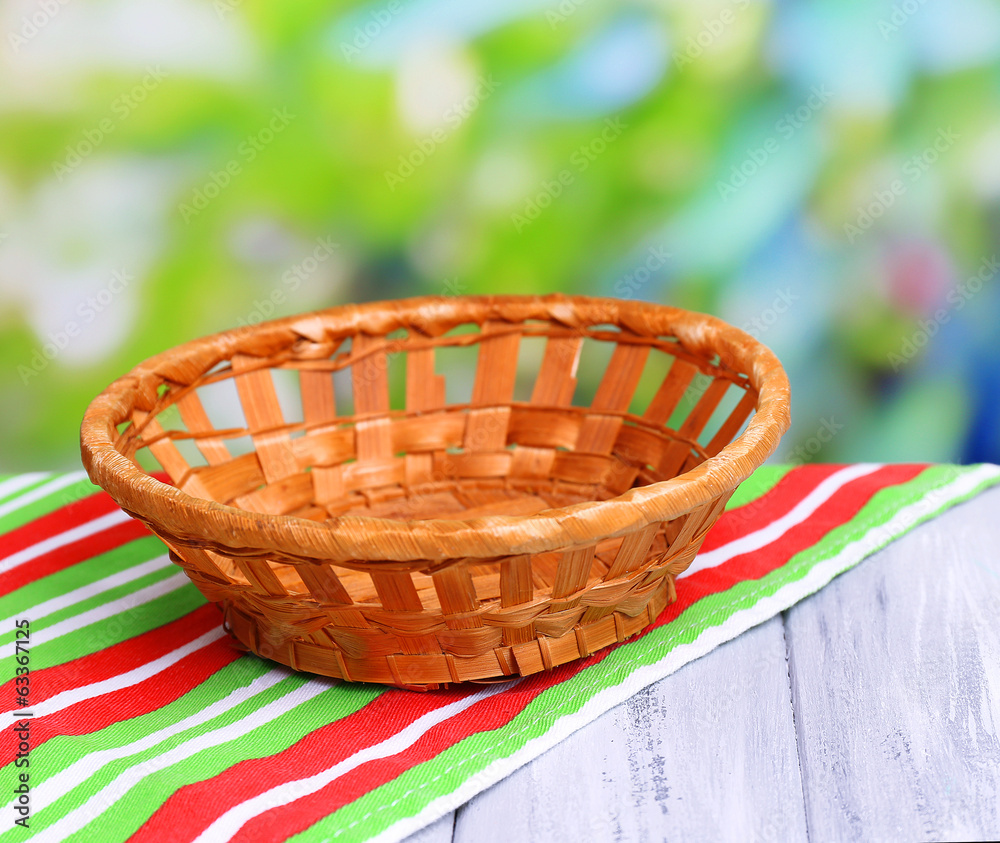 Empty wicker basket on wooden table, on bright background Empty wicker basket on wooden table, on bright background
