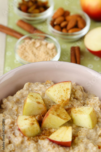Tasty oatmeal with apples and cinnamon on table close up