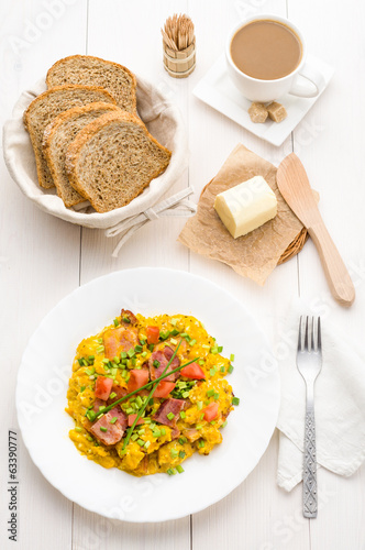 Scrambled eggs and bacon on white table