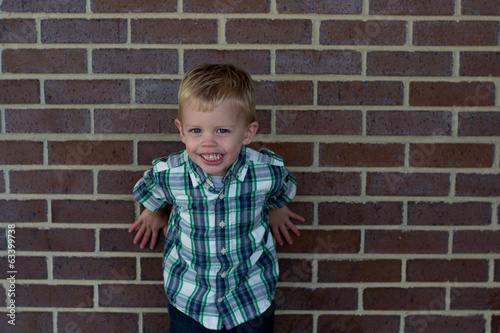 Little boy against brick wall. © mjvis