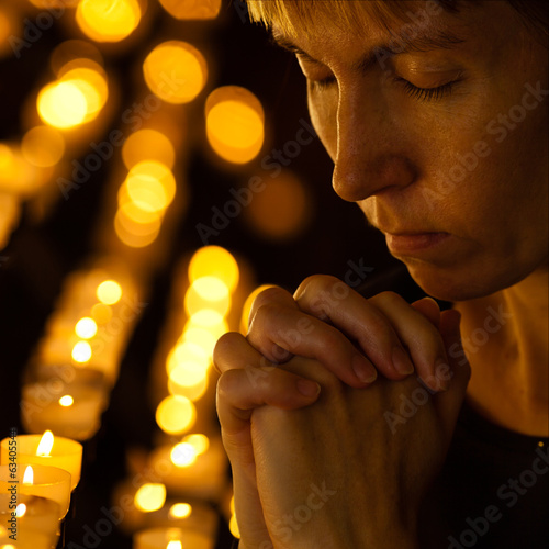 Prayer praying in Catholic church near candles. Religion concept photo