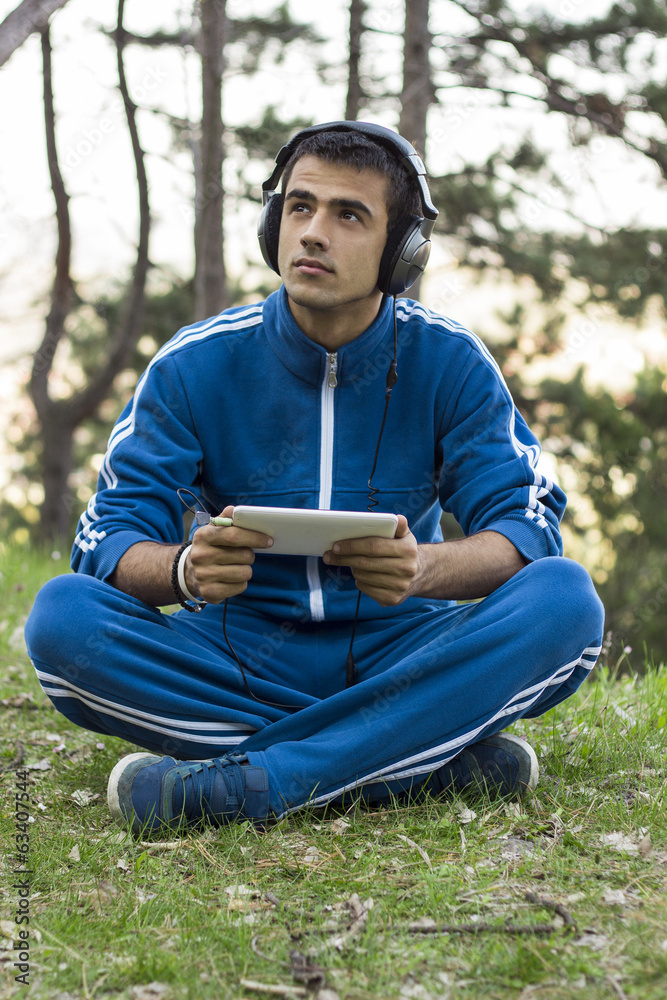 Obraz premium Man sits with tablet on the grass