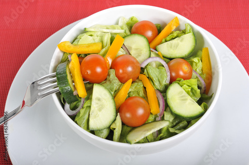 fork with cherry tomato, carrot in healthy salad bowl