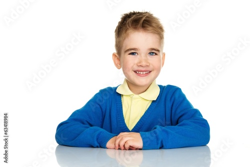 Cheerful little boy in blue cardigan and yellow shirt