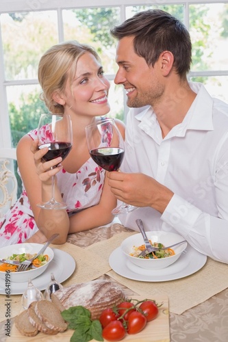 Loving couple with wine glasses looking at each other at dining