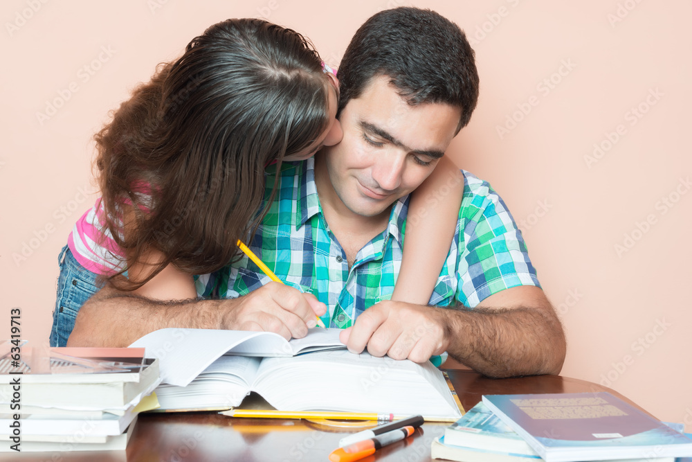 Young man studying with his daughter kissing him Young man studying with his daughter kissing him