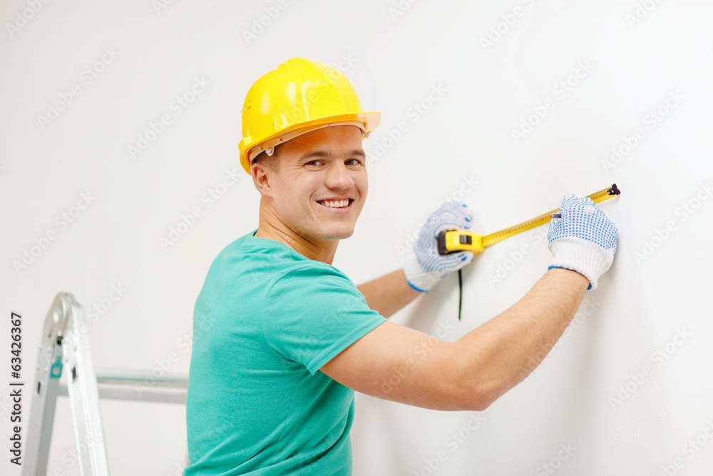 smiling man in protective helmet measuring wall smiling man in protective helmet measuring wall