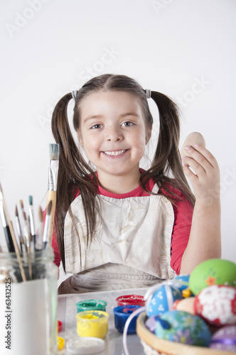 A happy little girl painting easter eggs photo