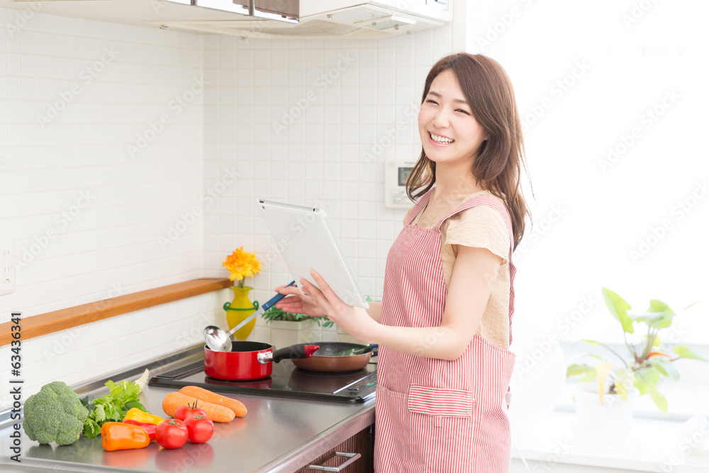 タブレットを見ながら料理をする女性