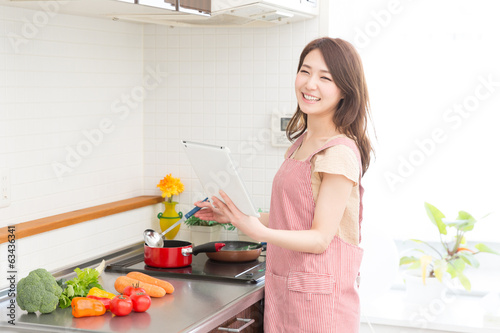 タブレットを見ながら料理をする女性