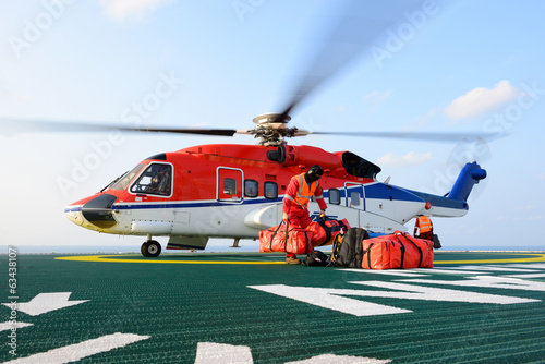 The helicopter landing officer loading baggage to helicopter at