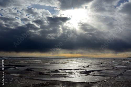 Sun through the stormy clouds at the frozen sea