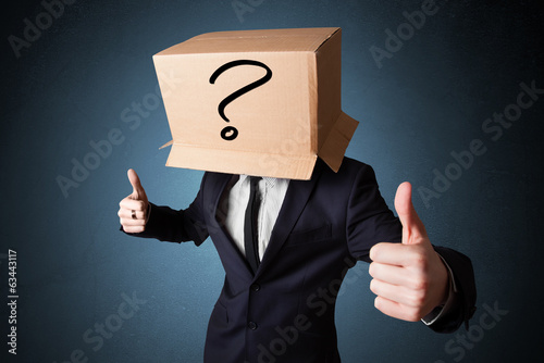 Businessman gesturing with a cardboard box on his head with ques photo