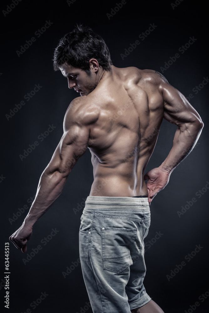Strong Athletic Man Fitness Model posing back muscles with trice Strong Athletic Man Fitness Model posing back muscles with trice