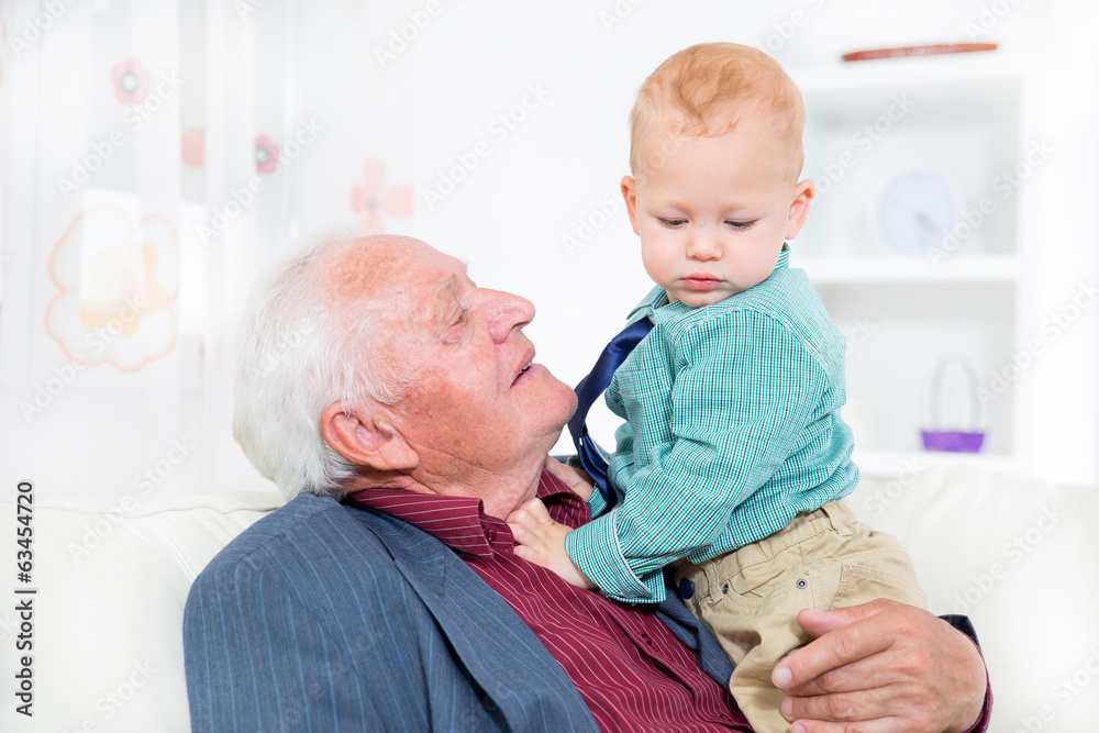 Cheerful grandfather and grandson sitting on the sofa