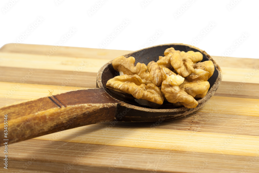 Walnut kernels into an old wooden spoon on a wooden board Walnut kernels into an old wooden spoon on a wooden board