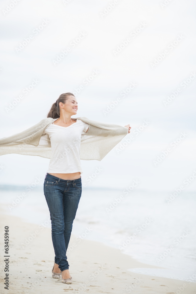 Full length portrait of young woman walking on cold beach Full length portrait of young woman walking on cold beach