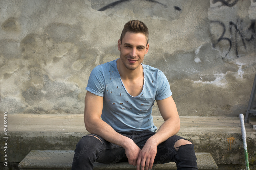 Smiling young man sitting on concrete steps Smiling young man sitting on concrete steps