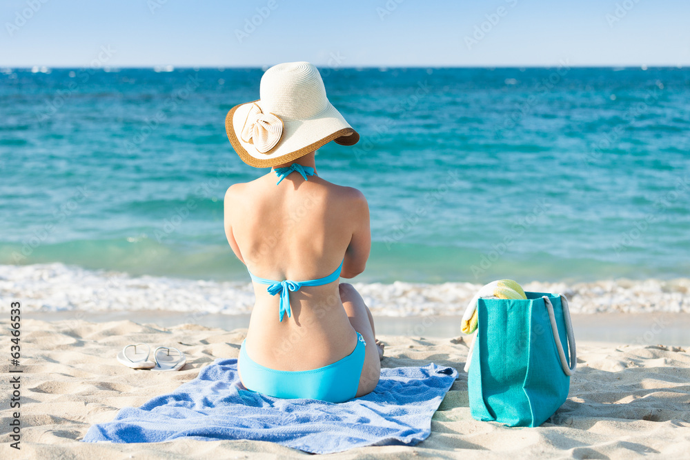 Woman in bikini relaxing on beach towel enjoying the ocean view Woman in bikini relaxing on beach towel enjoying the ocean view