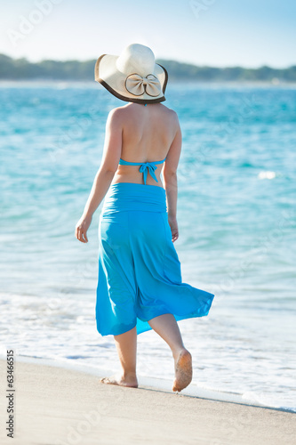 Woman Wearing Sunhat Walking On Beach