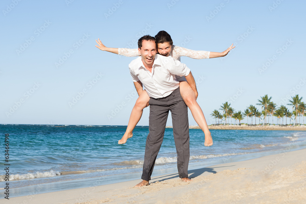 Man Giving Piggyback Ride To Woman At Beach Man Giving Piggyback Ride To Woman At Beach