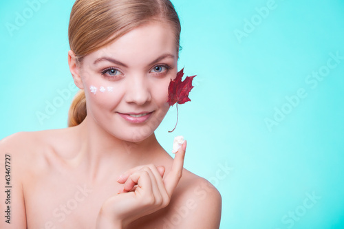 Skin care. Face of young woman girl with red maple leaf. photo