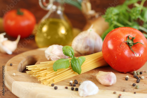 Pasta with tomatoes, olive oil and basil on wooden background