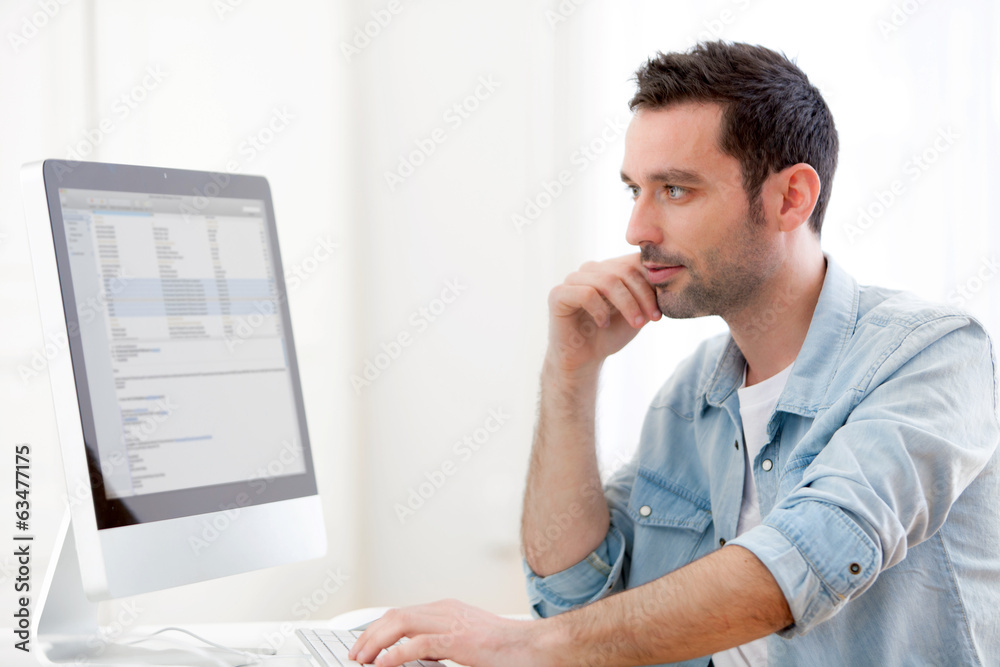 Fototapeta premium Portrait of a young relaxed man using computer