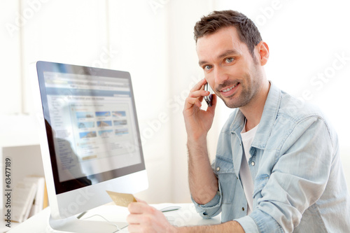 Young relaxed man paying online with his credit card