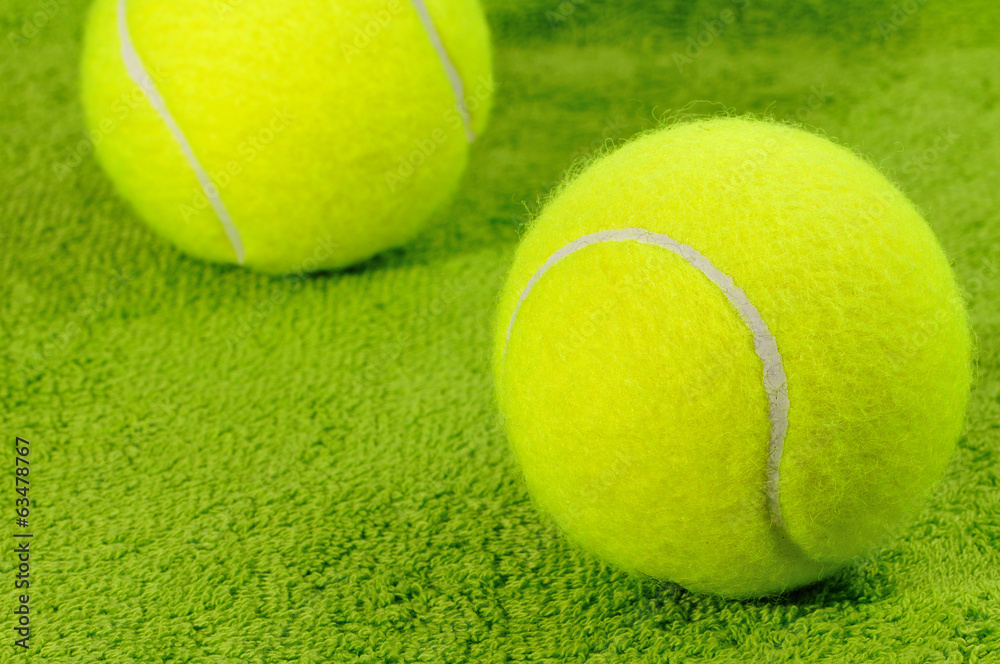 Two yellow tennis balls on green surface