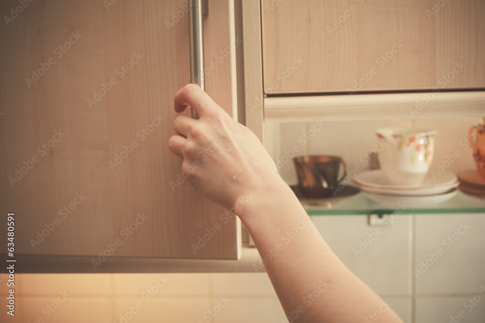 © LoloStock - Hand opening kitchen cupboard