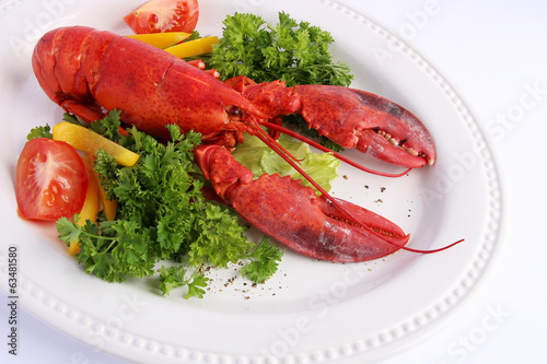 Cooked lobster with various vegetables on white plat