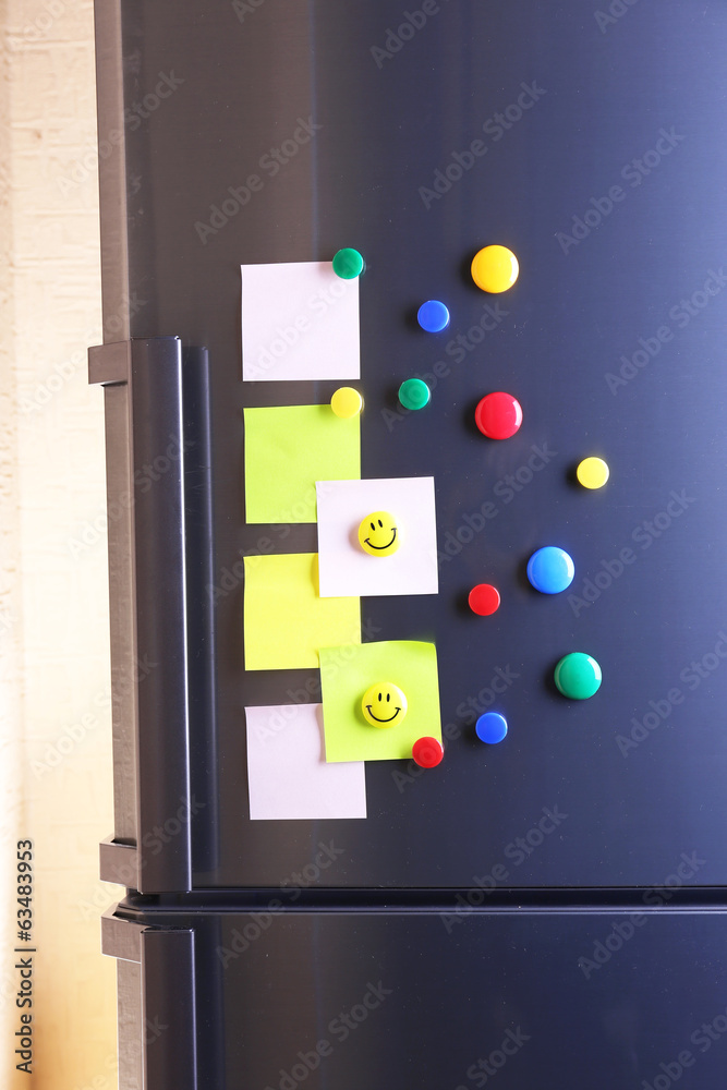 Empty paper sheets and colorful magnets on fridge door Empty paper sheets and colorful magnets on fridge door