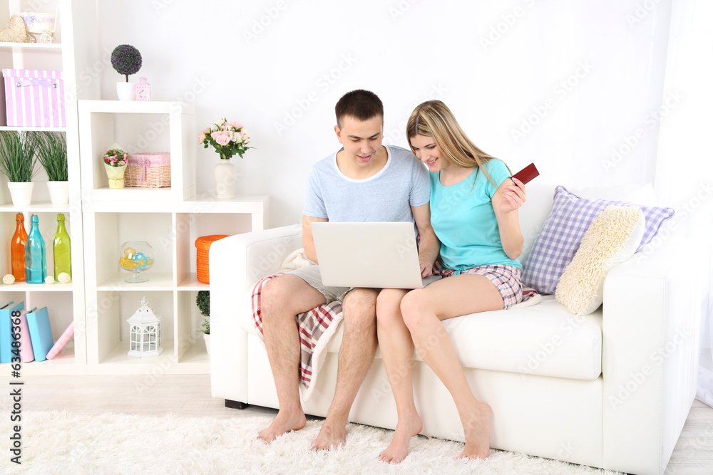 Loving couple sitting with laptop and credit card Loving couple sitting with laptop and credit card