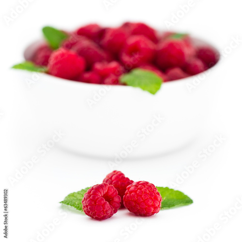 Three red raspberries with fresh mint leaves