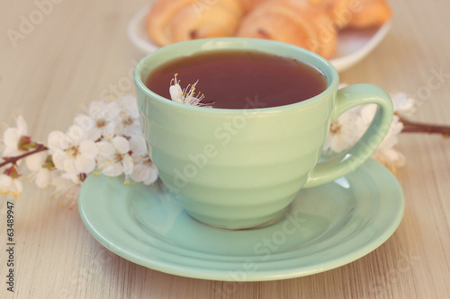 Cup of tea and croissants near blossoming branches