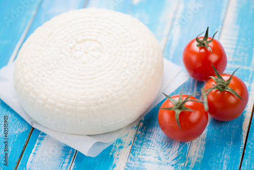Adygea cheese and cherry tomatoes, blue wooden background